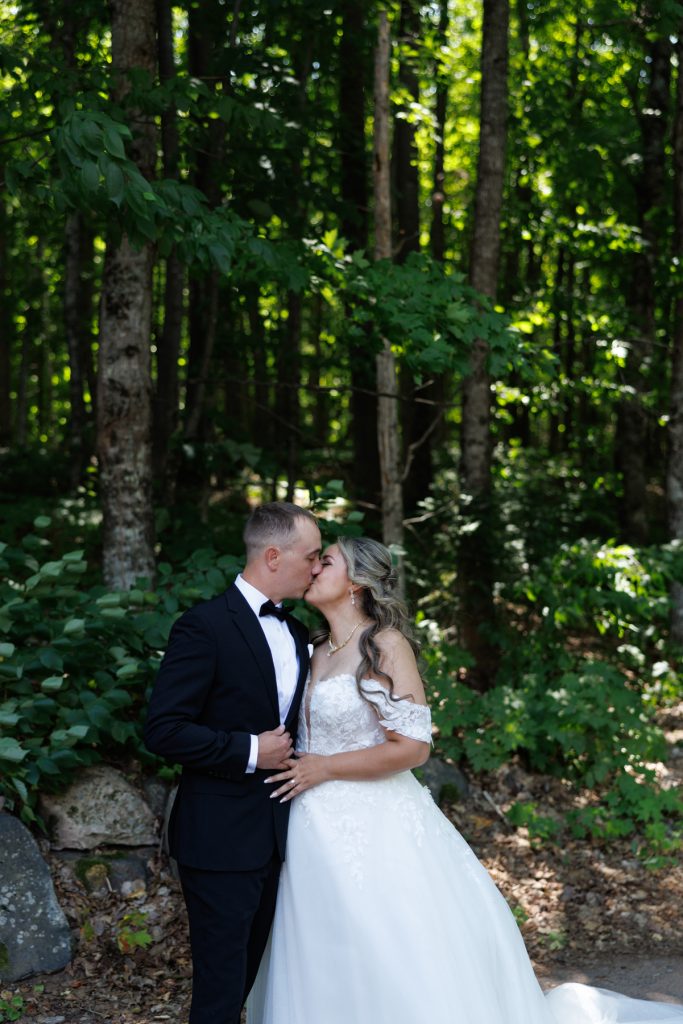 Bianca and Nick, the wedding couple, share a tender kiss surrounded by lush greenery