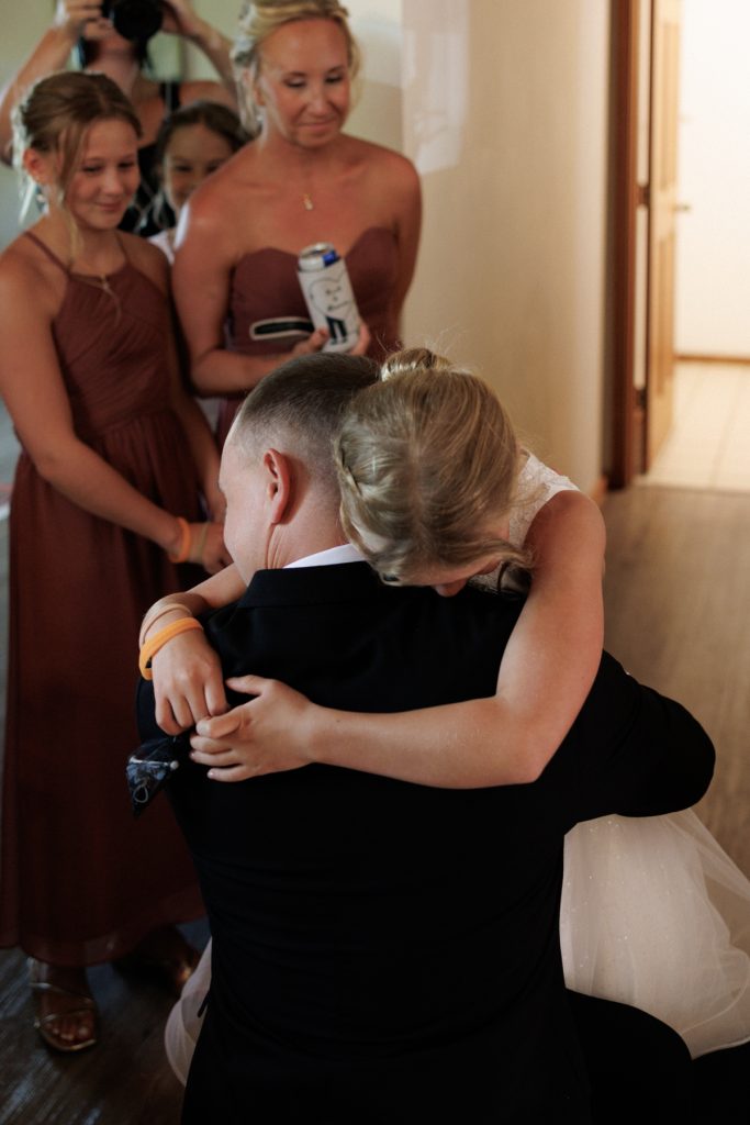 Bride and groom sharing a heartwarming hug with a flower girl at a Lakewoods Resort