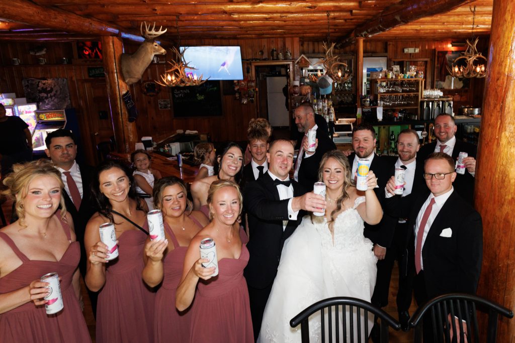 Wedding party at Lakewoods Resort in Cable, Wisconsin, raising beers in a celebratory group portrait