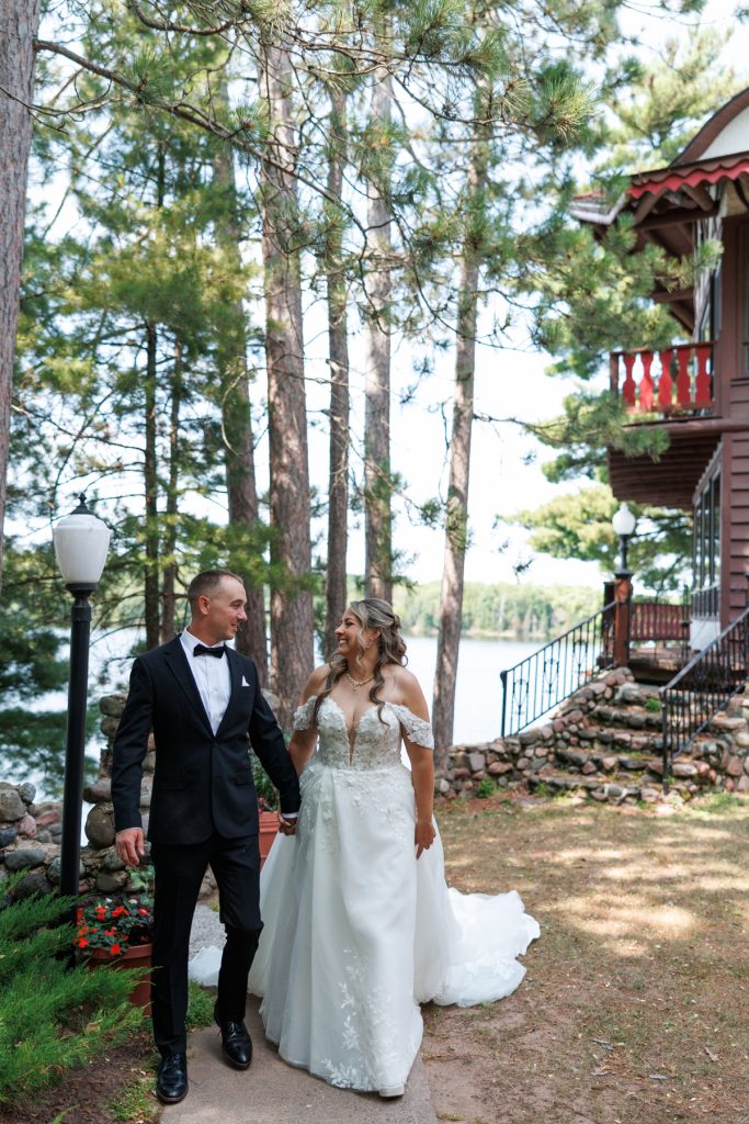 Bianca and Nick, the newly married couple, walk hand-in-hand along a lakeside path at Lakewoods