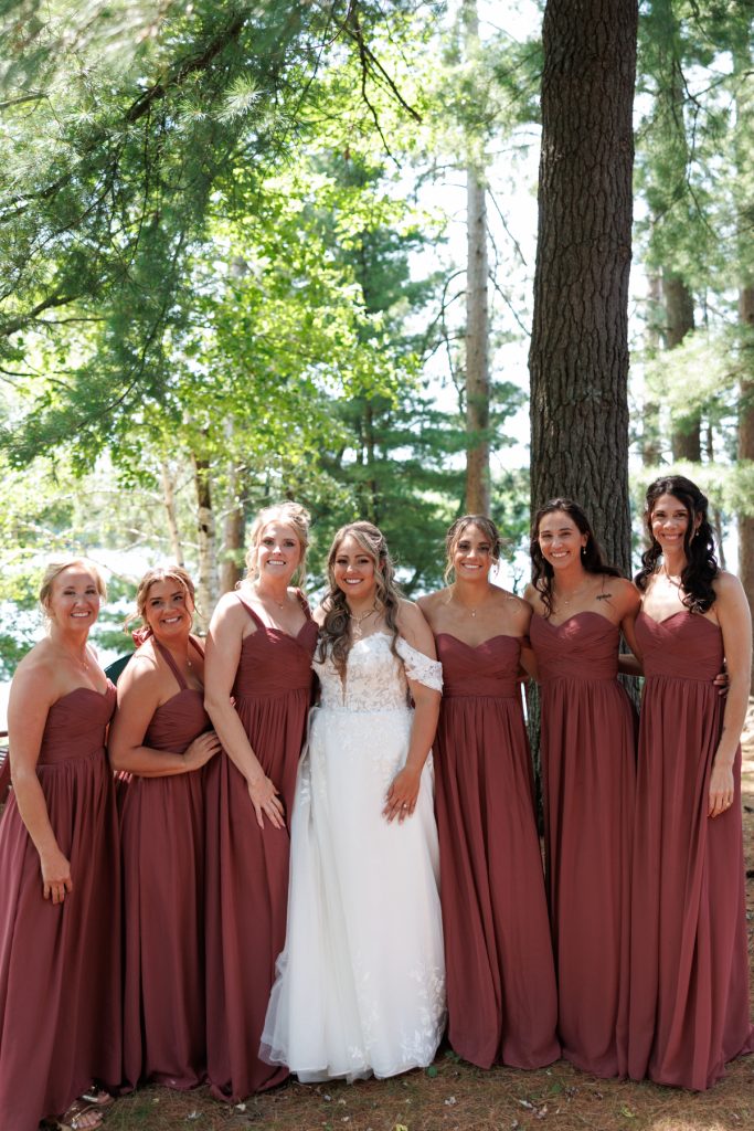Bride and bridesmaids in matching maroon dresses pose for a Lakewoods Resort wedding photography portrait