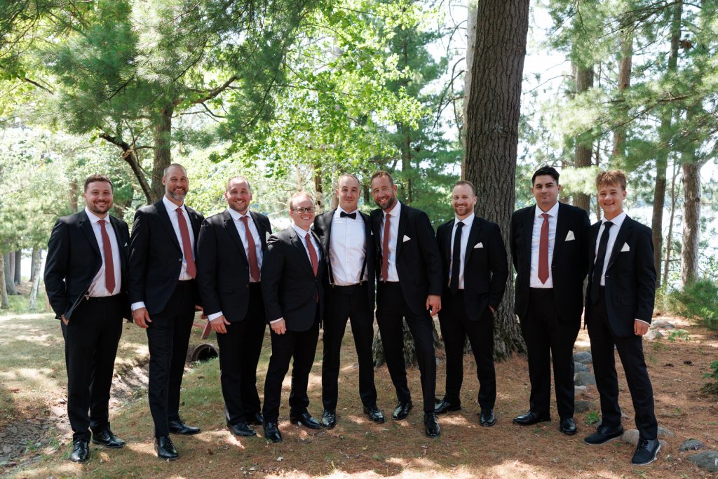 Group portrait of the groom and groomsmen in suits and ties standing outdoors
