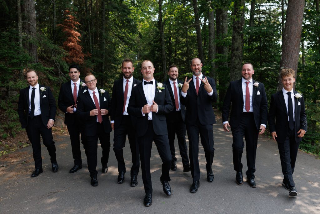 Groom and groomsmen in formal wear posing for a group photo during a destination wedding