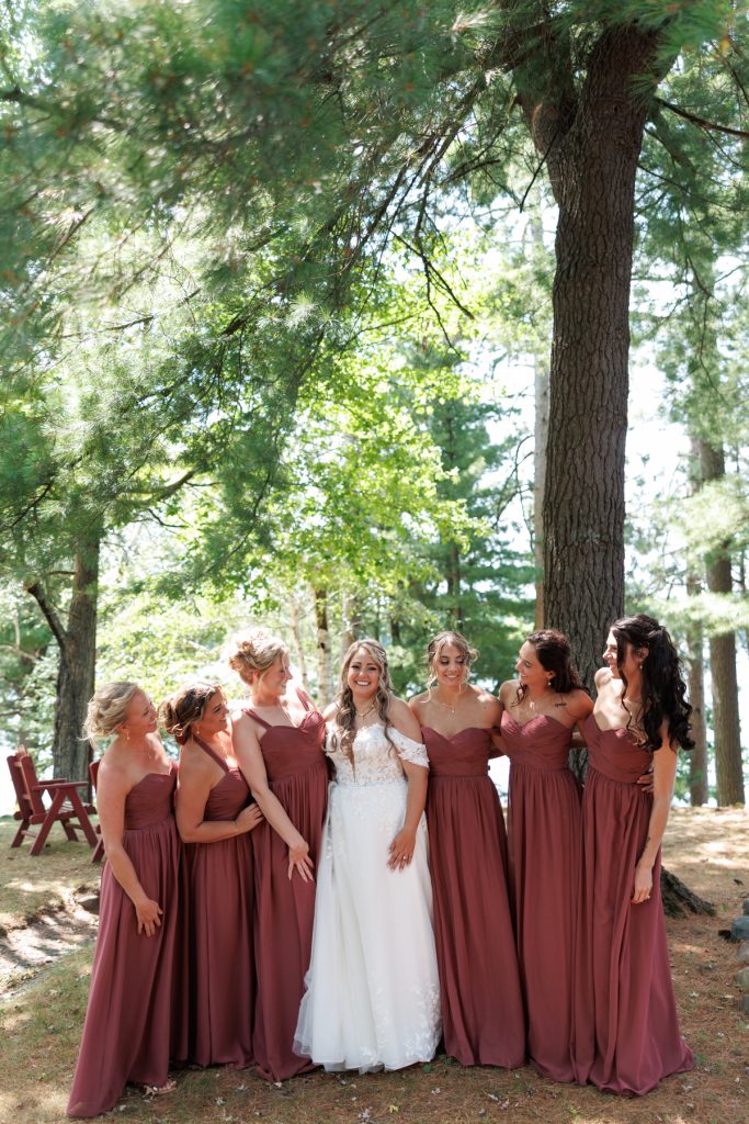 Bride and bridesmaids in matching maroon dresses pose for a portrait at a Lakewoods Resort