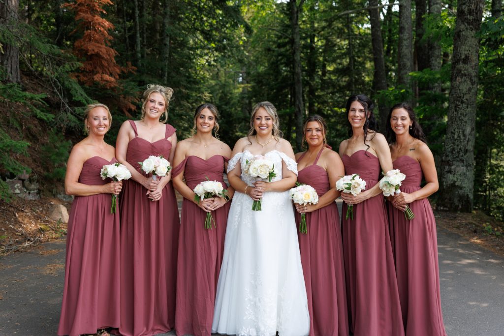 Bride and bridesmaids in maroon dresses pose for a portrait during a Lakewoods Resort wedding
