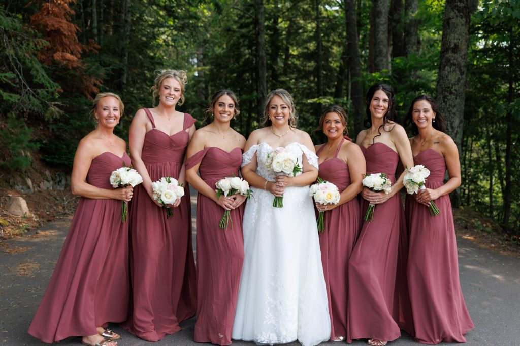 Bride and bridesmaids in maroon dresses pose for a wedding photograph at Lakewoods Resort