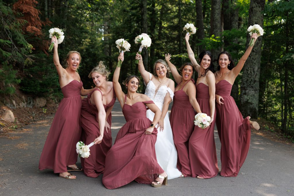 Bride and bridesmaids in maroon dresses celebrating with bouquets during a destination wedding at Lakewoods