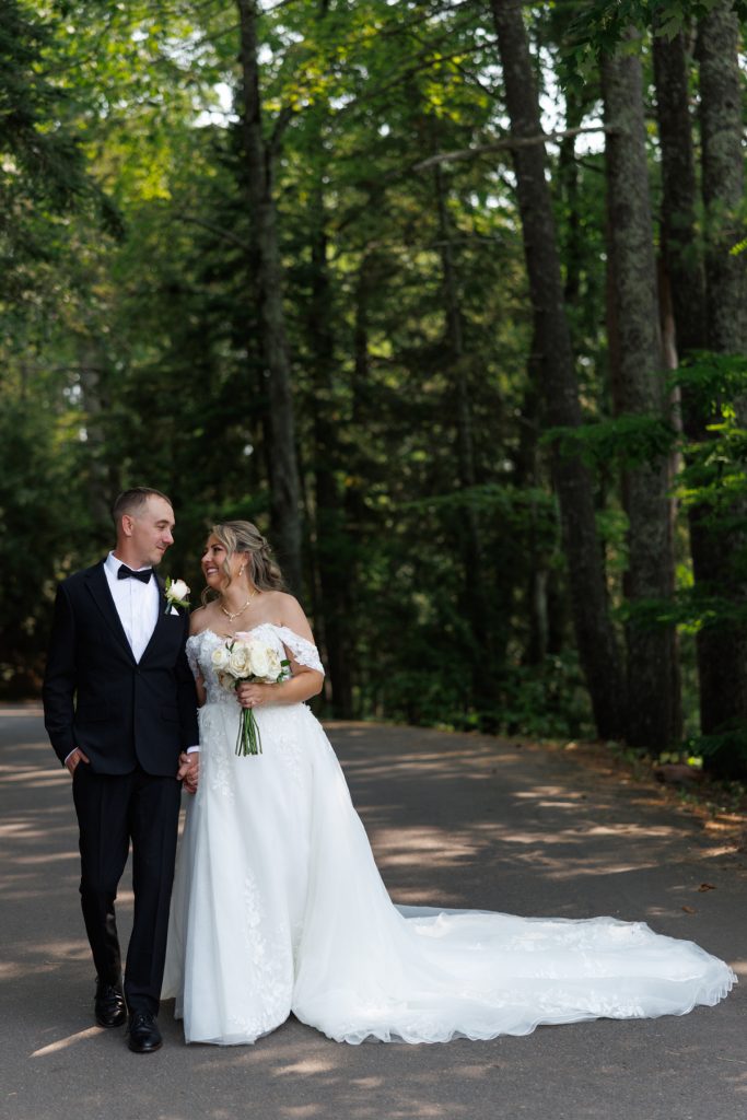 Bianca and Nick, the happy couple, walk hand-in-hand on a scenic road at Lakewoods Resort