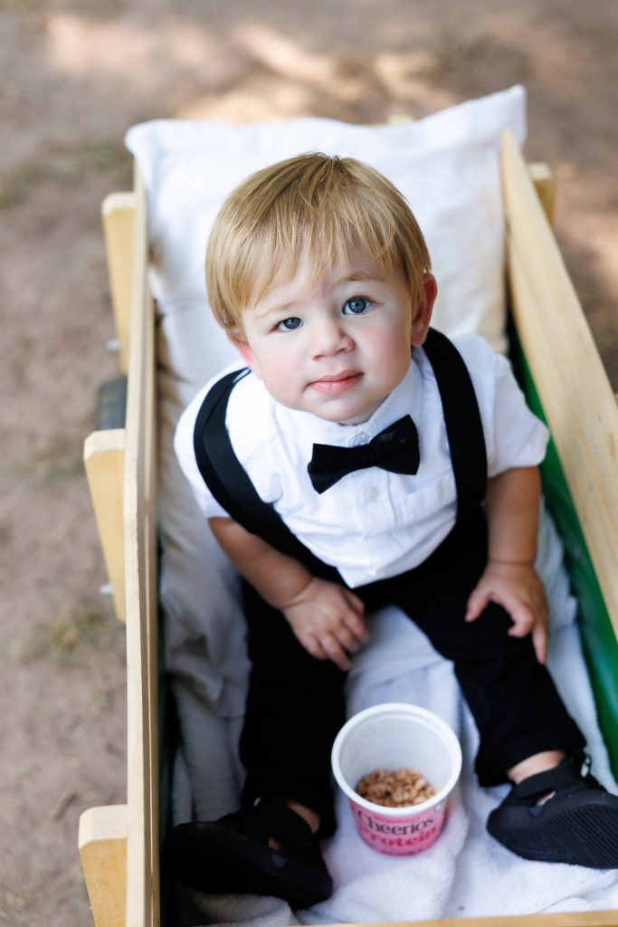 Adorable young boy dressed in a tuxedo with bow tie and suspenders sits
