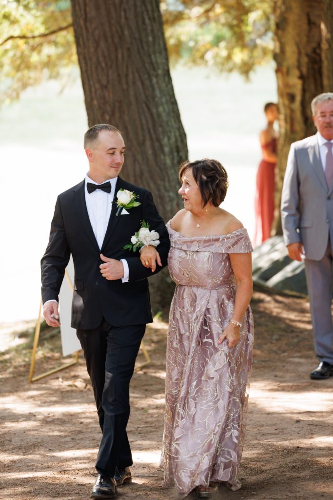Groom in a tuxedo walking with his mother at a Lakewoods Resort wedding in Cable