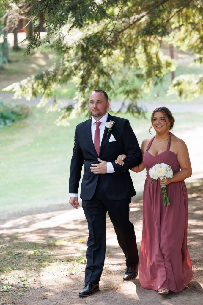 Groom and bridesmaid walking together at a Lakewoods Resort wedding in Cable, Wisconsin, captured