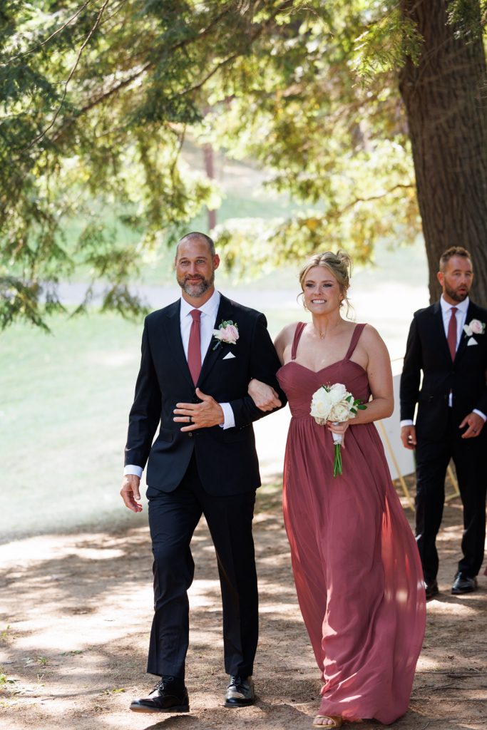 Bride and groom walking hand-in-hand down a grassy aisle at a Lakewoods Resort wedding