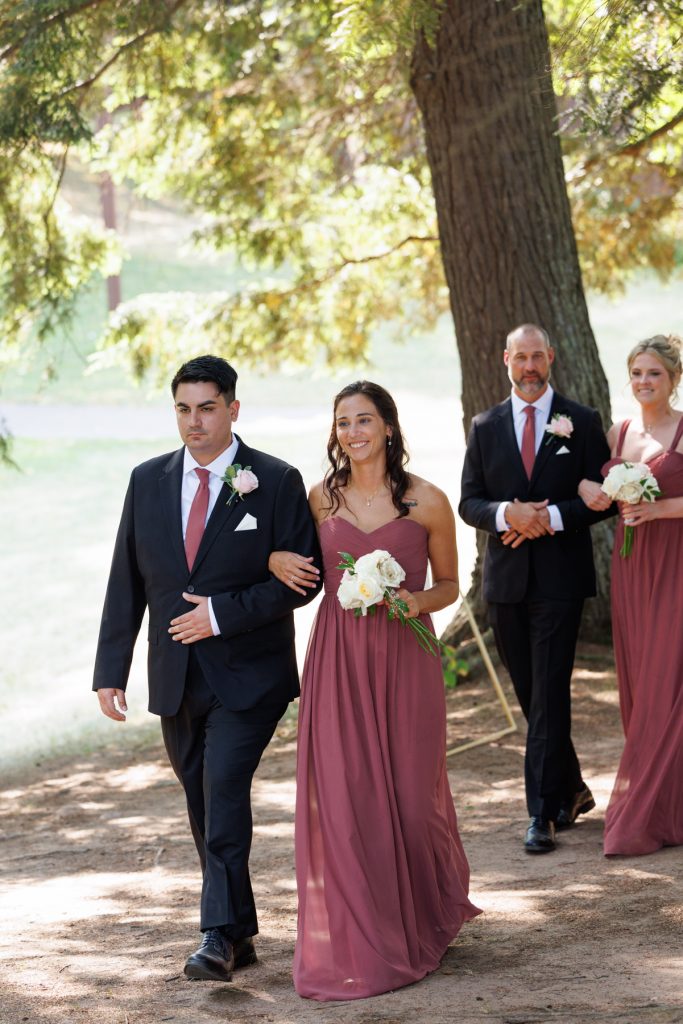 Bride in a long pink gown walks arm-in-arm with her groom during their Lakewoods Resort
