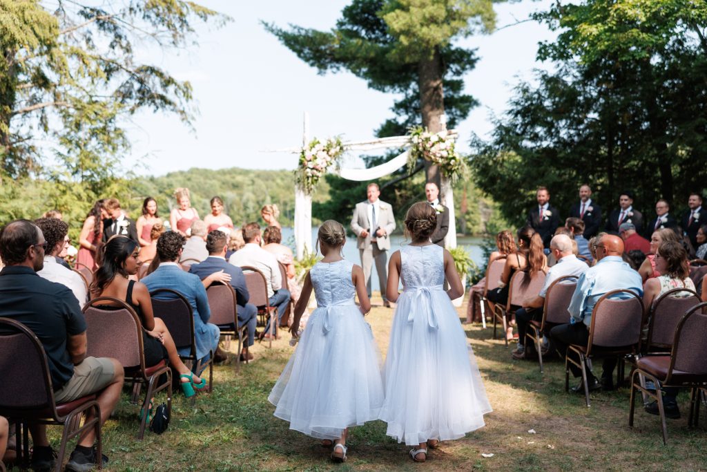 Two flower girls in light blue dresses walk down the aisle at a Lakewoods Resort