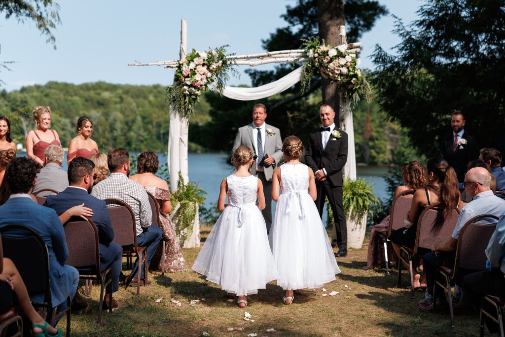 Beautiful wedding ceremony at Lakewoods Resort in Cable, Wisconsin, featuring a floral-adorned wooden arch overlooking