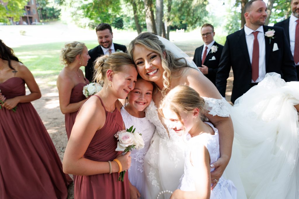 Bride Bianca embraces flower girls and bridesmaids at a Lakewoods Resort wedding in Cable, Wisconsin
