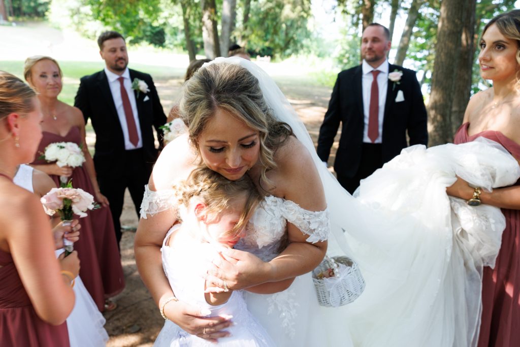 Bride Bianca embracing a flower girl at Lakewoods Resort wedding, surrounded by bridesmaids and groomsmen
