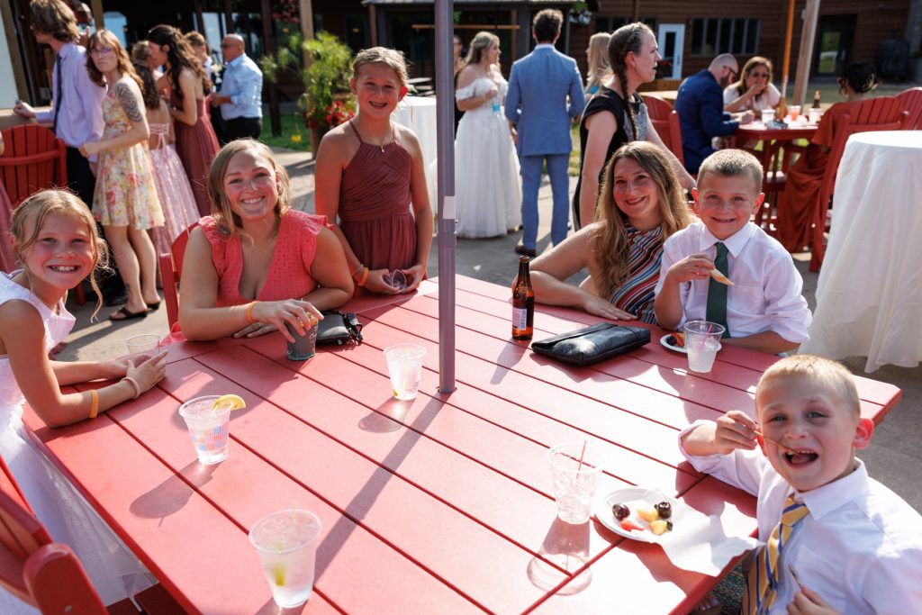 Group of children and adults smiling at a table during a Lakewoods Resort wedding