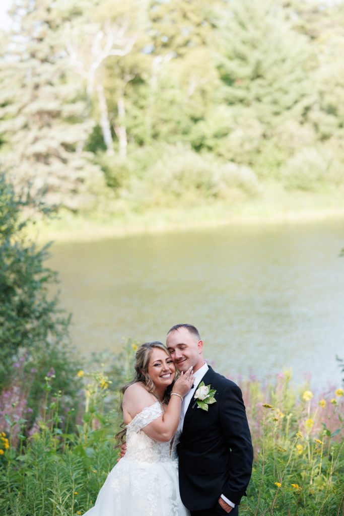 Bianca and Nick, the happy couple, embrace near Lake Namekagon at their Lakewoods Resort wedding