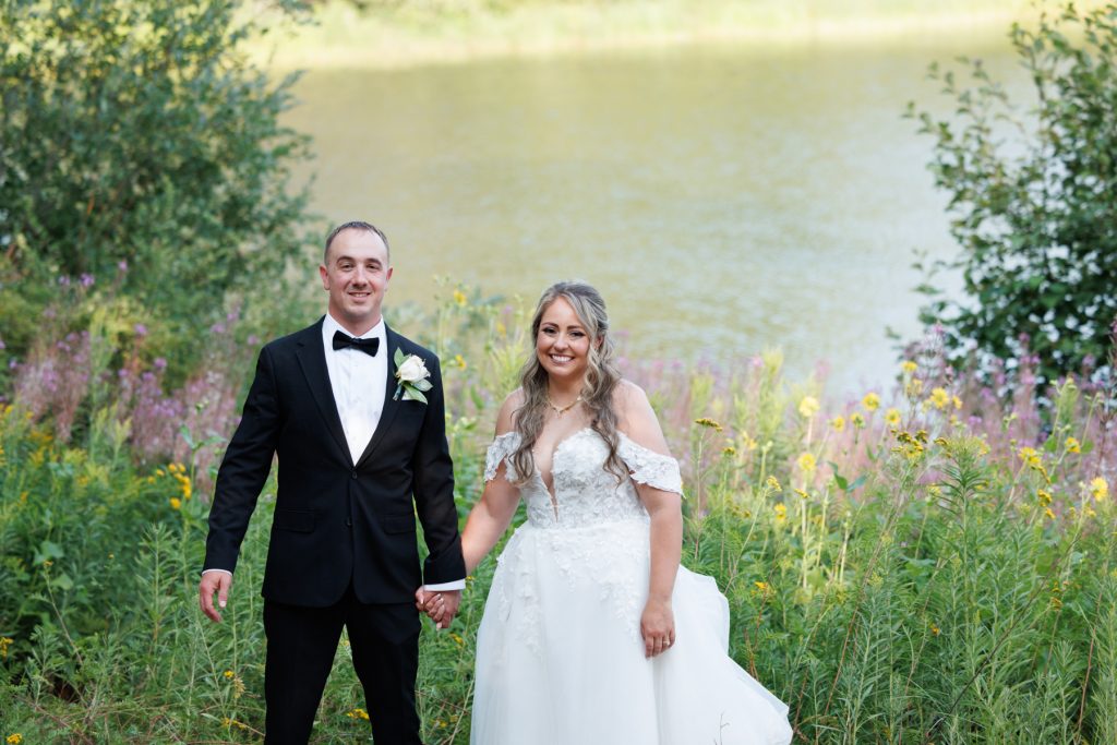Bianca and Nick, the Lakewoods Resort wedding couple, smiling and holding hands in front