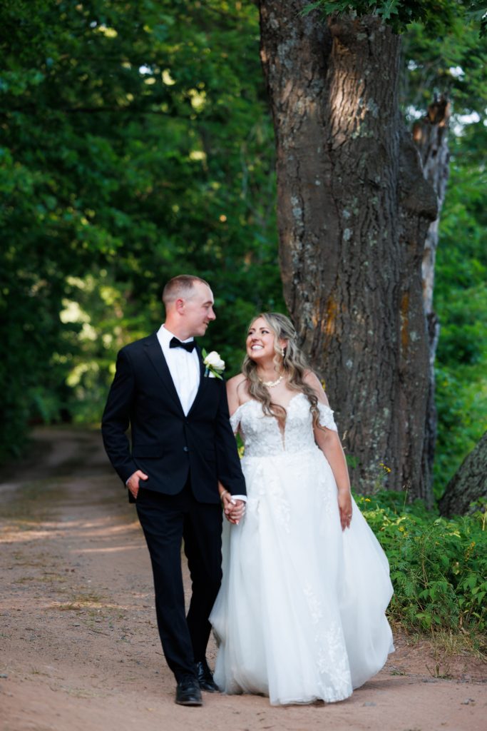 Bianca and Nick, the Lakewoods Resort wedding couple, stroll hand-in-hand down a path at Cable