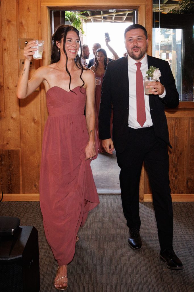 Bianca and Nick, the Lakewoods Resort wedding couple, joyfully exit a building, toasting with drinks