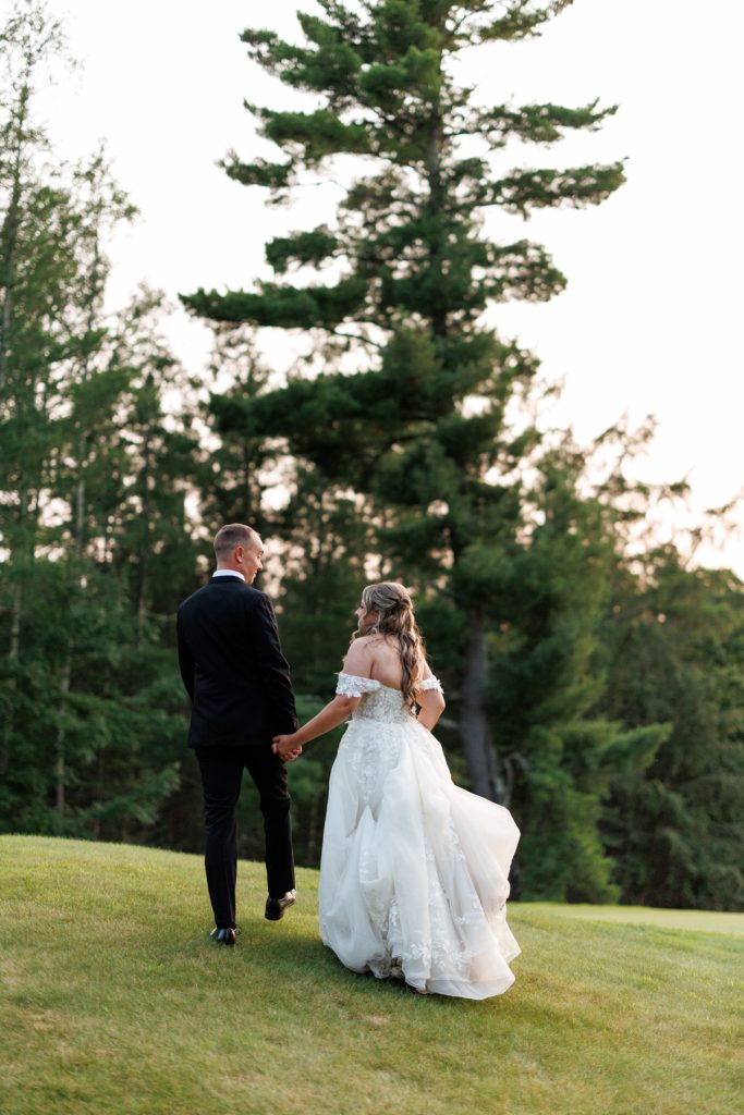 Bianca and Nick, the newlyweds, walk hand-in-hand away from the camera at Lakewoods Resort