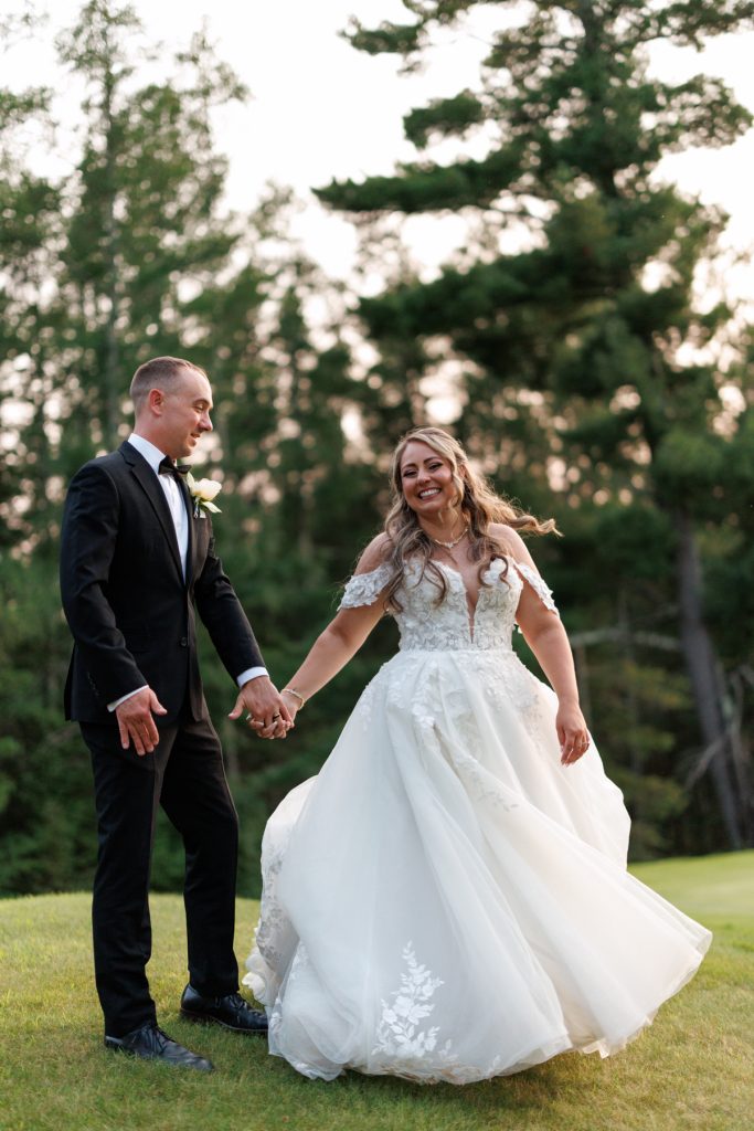Bianca and Nick, the happy couple, walk hand-in-hand at their Lakewoods Resort wedding in Cable