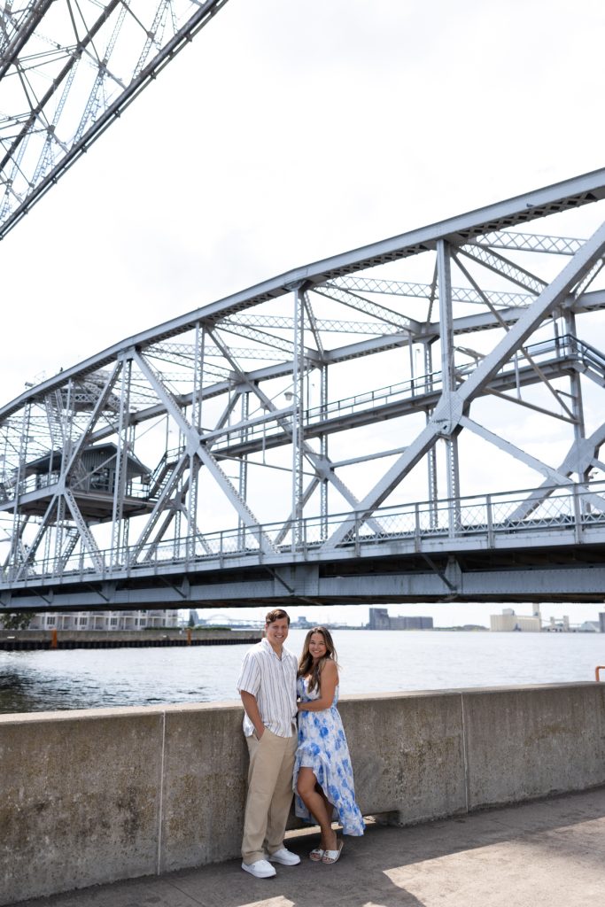 Cassie and Daniel, the engaged couple, pose for an engagement photo session near a bridge