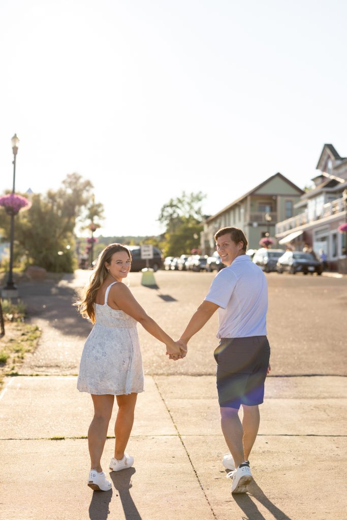 Cassie and Daniel, an engaged couple, hold hands and walk away from the camera along